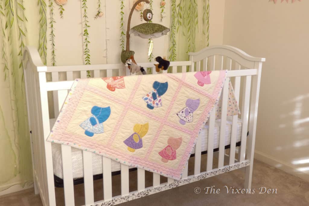 painted and stenciled crib shown with handmade quilt and mobile