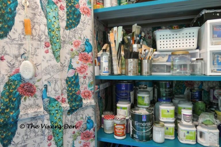 close up of metal garage cabinet lined with peacock fabric and paint supplies