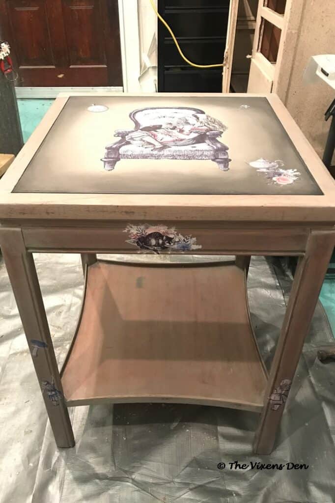 front view of several Dixie Belle Alice in Wonderland transfers on the top, sides and legs of a square cherry side table