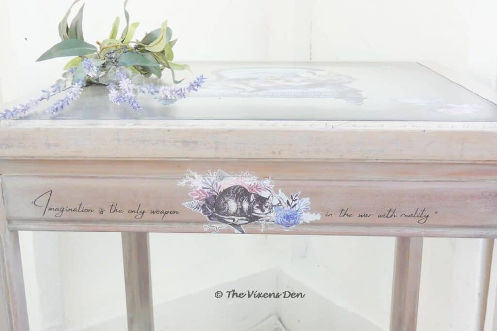front view of table top edge with Alice in Wonderland transfer of Cheshire cat with a quote from the story