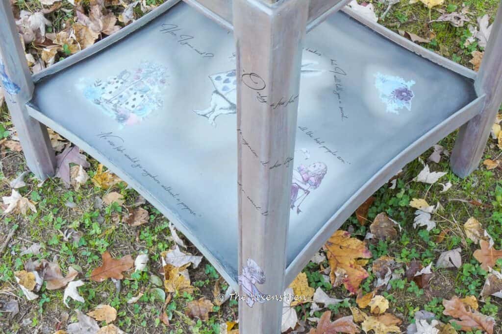 angle view of end table with quotes wrapped around the leg and Alice in Wonderland images on the bottom shelf