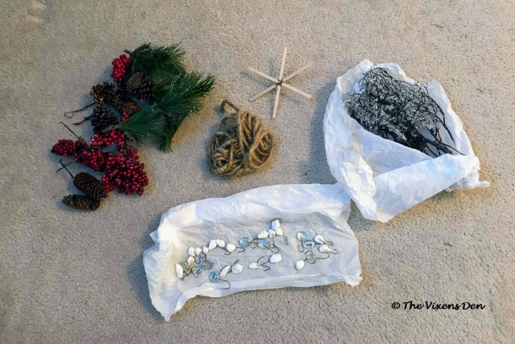 groups of Christmas tree ornaments: pinecone, greenery, and berry picks; white rock and clear glass marble ornaments; a clump of twine; icicle picks; and a popsicle star