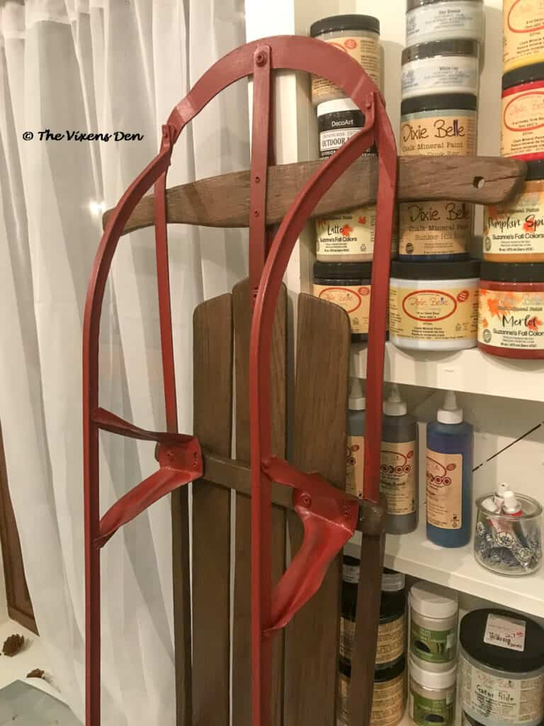 closeup of refinished vintage sled against a wall of shelves with Dixie Belle products