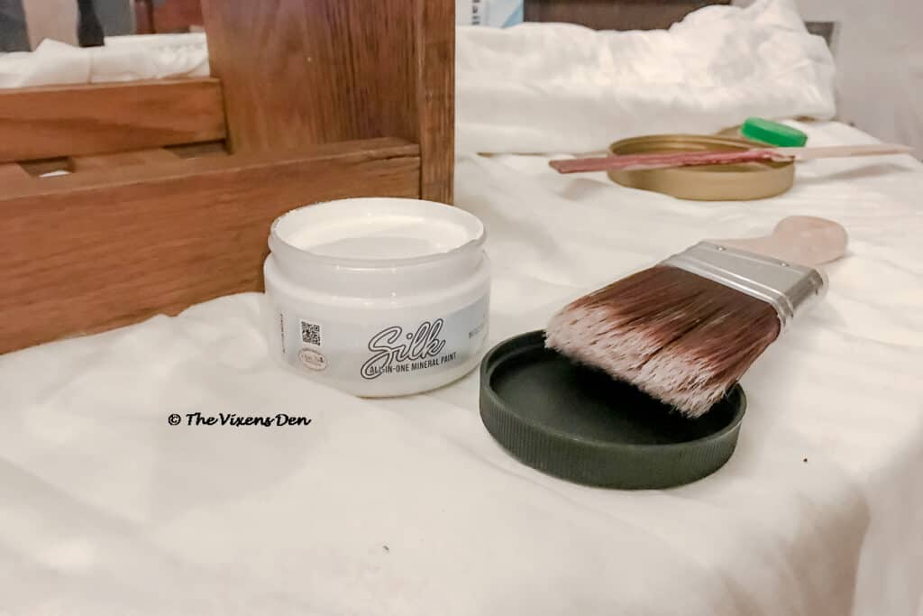 an open container of Dixie Belle Silk paint in White Cap and a mini angle brush