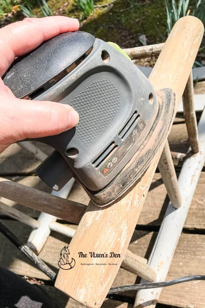 sanding flaking paint off of a ladderback chair