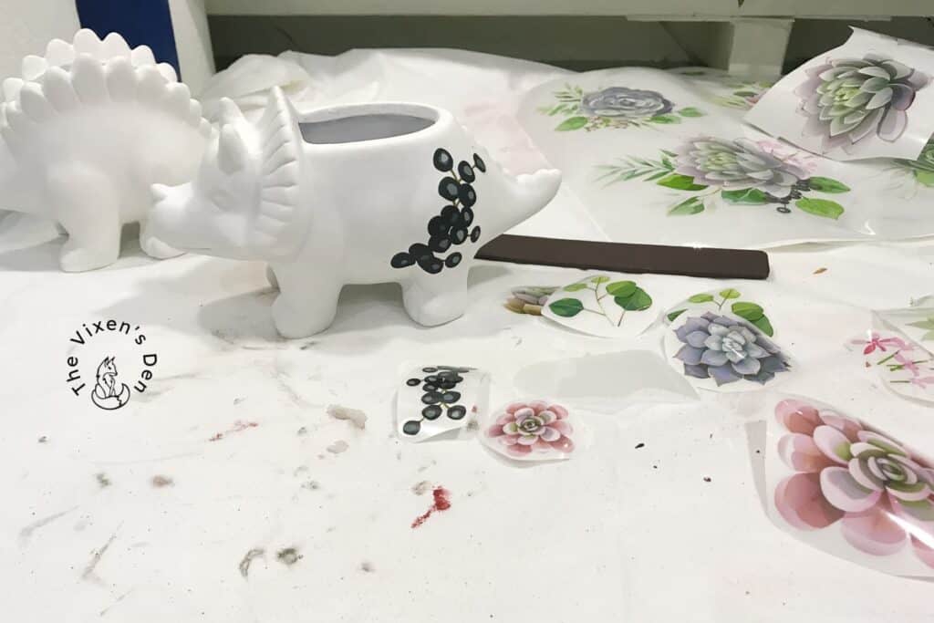 ceramic dinosaurs with rubbing stick and transfers being applied