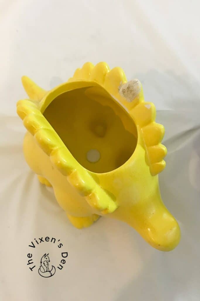 yellow ceramic dinosaur with repaired back plate