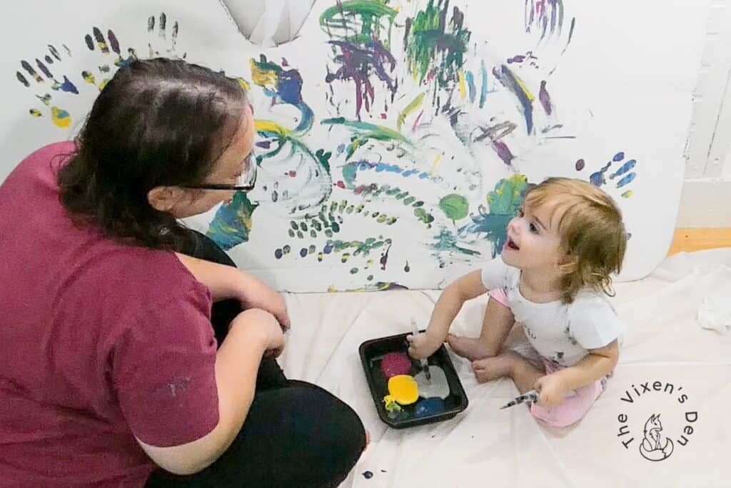 Toddler and woman interacting while painting