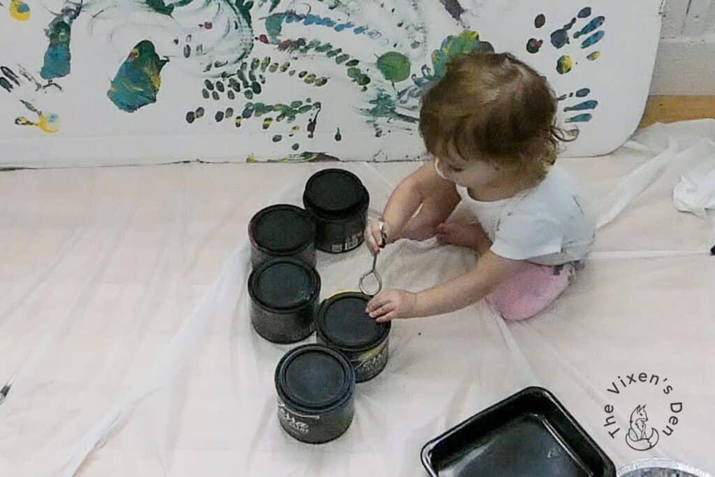 Toddler with jars of paint