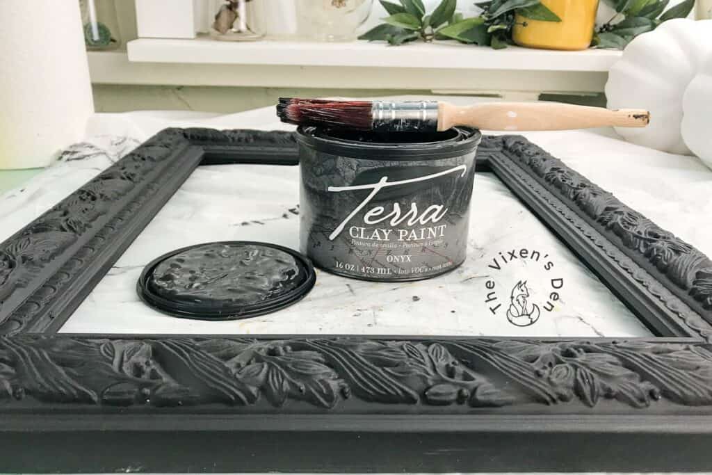 process - painting picture frame with Onyx Terra Clay Paint and a paint brush