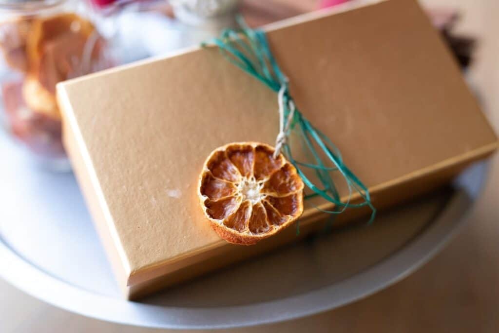 Dried Clementine Orange ornament tied onto a gift box with green raffia