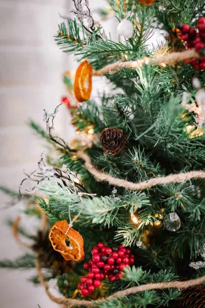 closeup of tabletop Christmas tree with dried clementine orange slice ornament and DIY white rock and glass marble ornaments