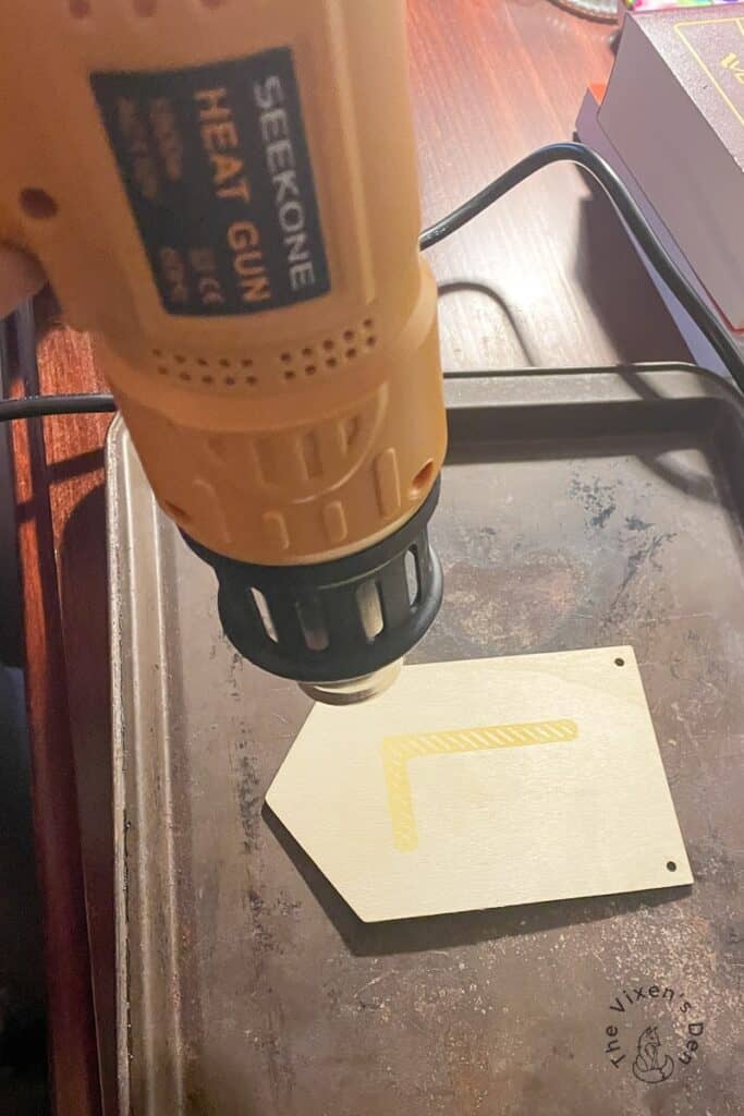 Applying heat to woodburning paste on a sign blank using a seekone heat gun