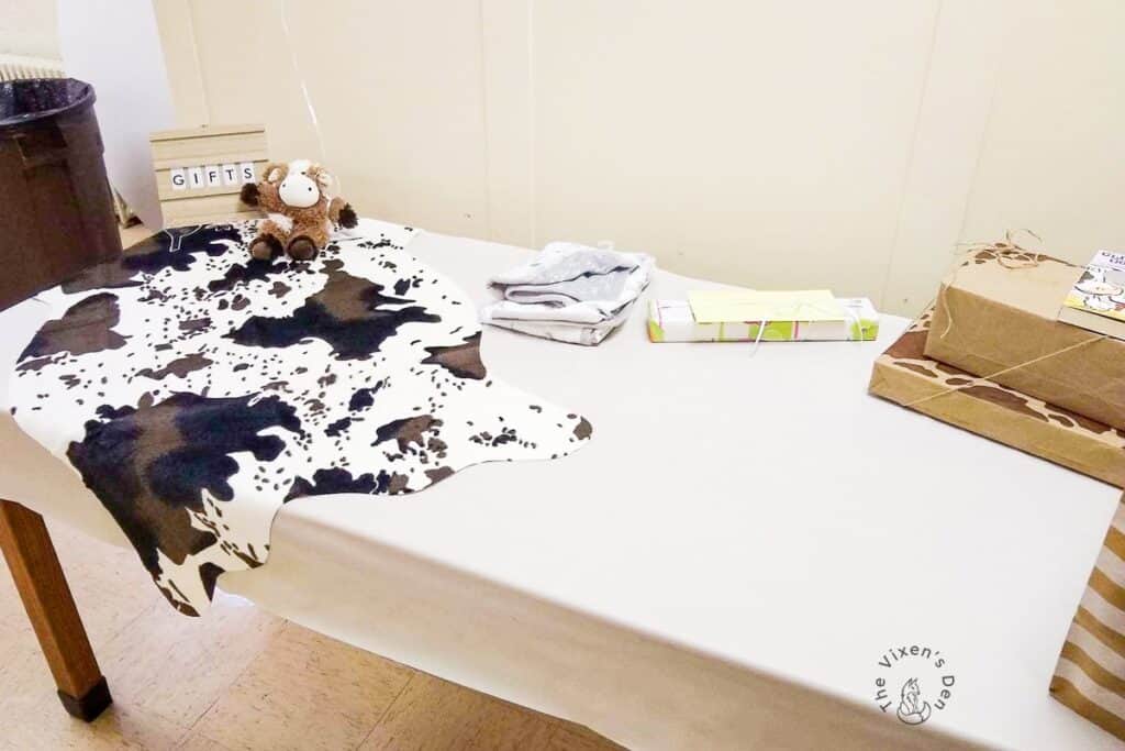 Baby shower gift table with faux cowhide rug and gifts