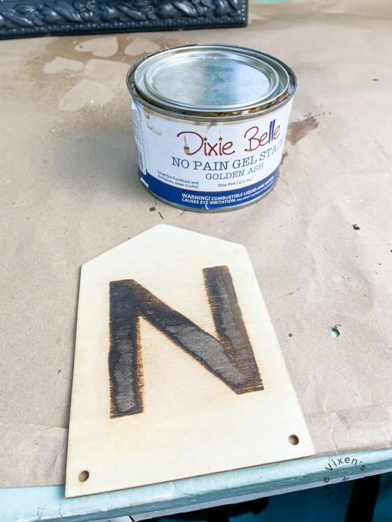 Woodburned letter with a can of no pain gel stain in golden ash