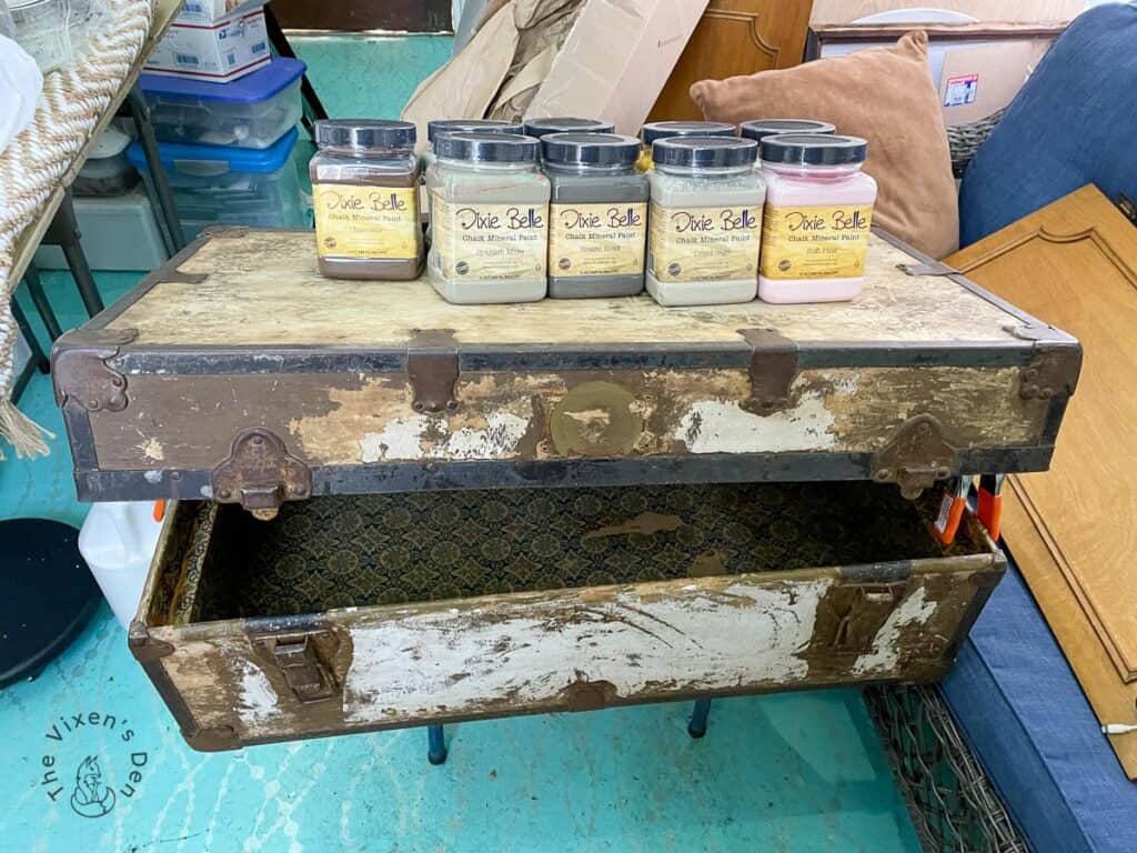 Old Wood Trunk Makeover-trunk lid with jars of Dixie Belle paint weighing it down