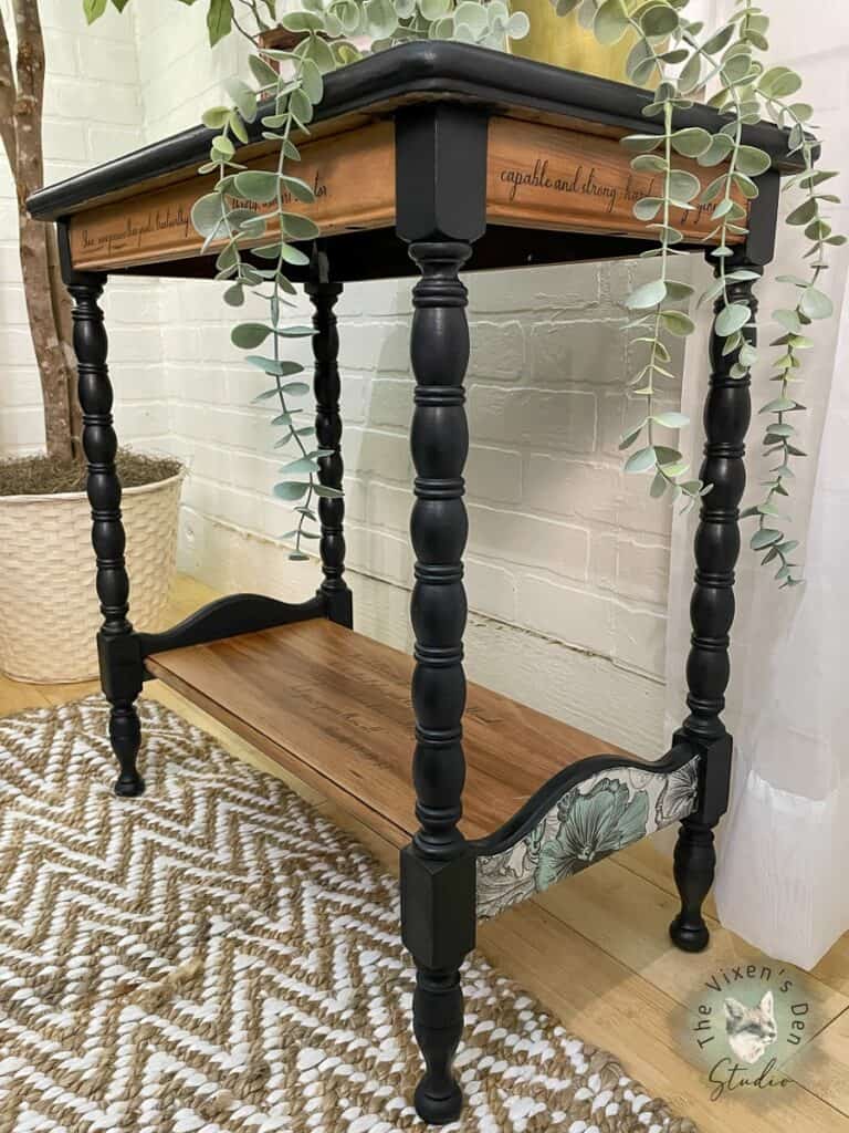 A black console table with a plant on it.