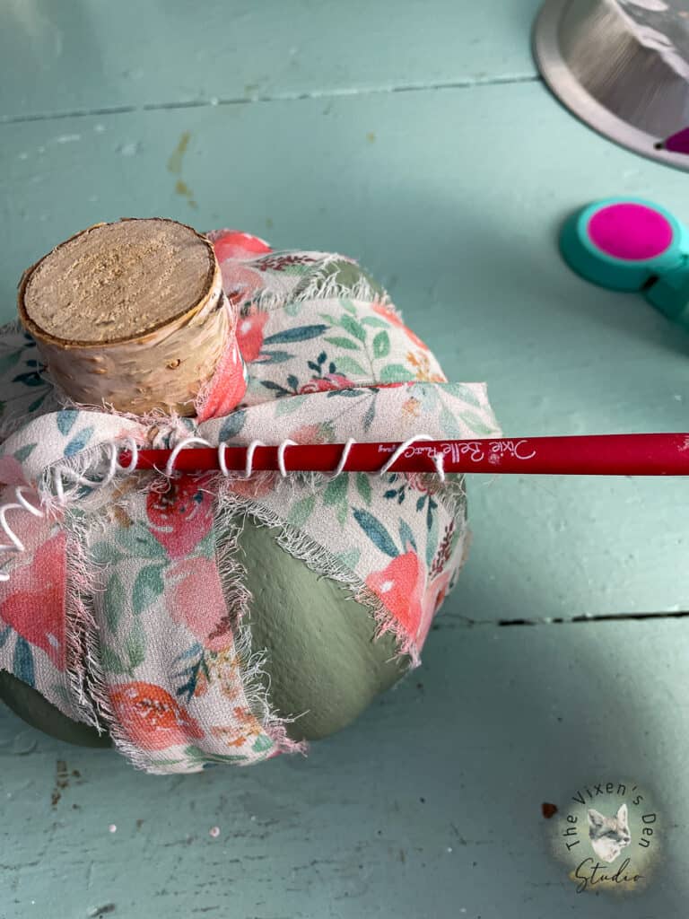 A pumpkin with a paintbrush handle.