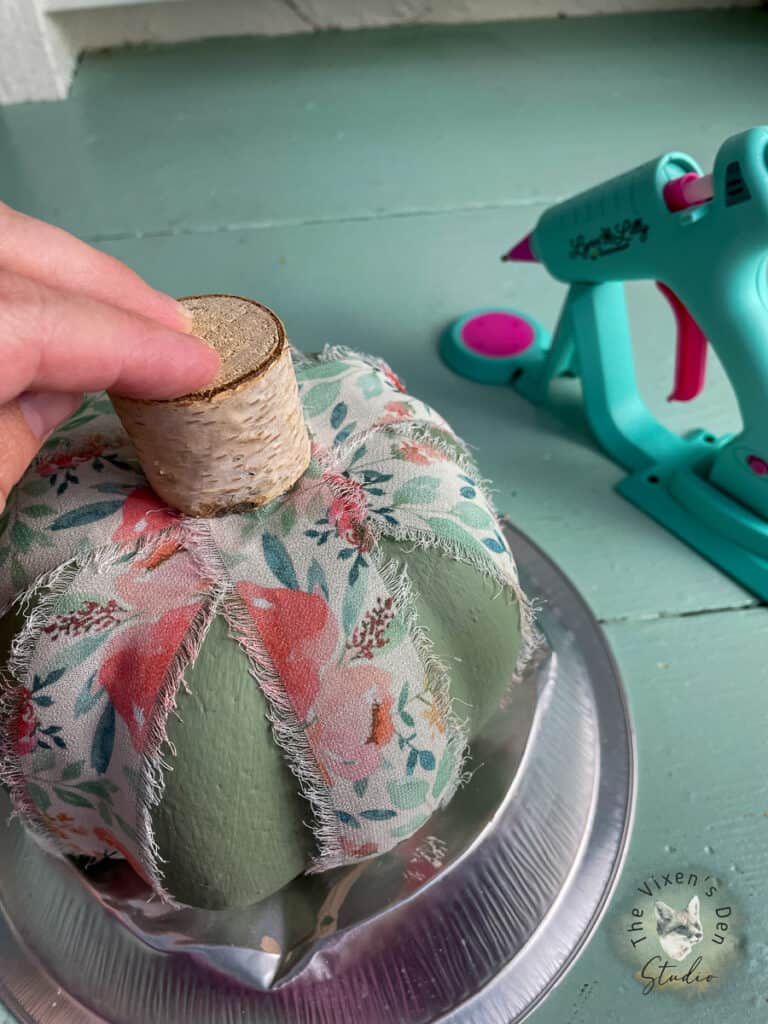 A person using a glue gun to make a pumpkin.