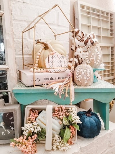 A mantle with pumpkins, flowers and a clock.