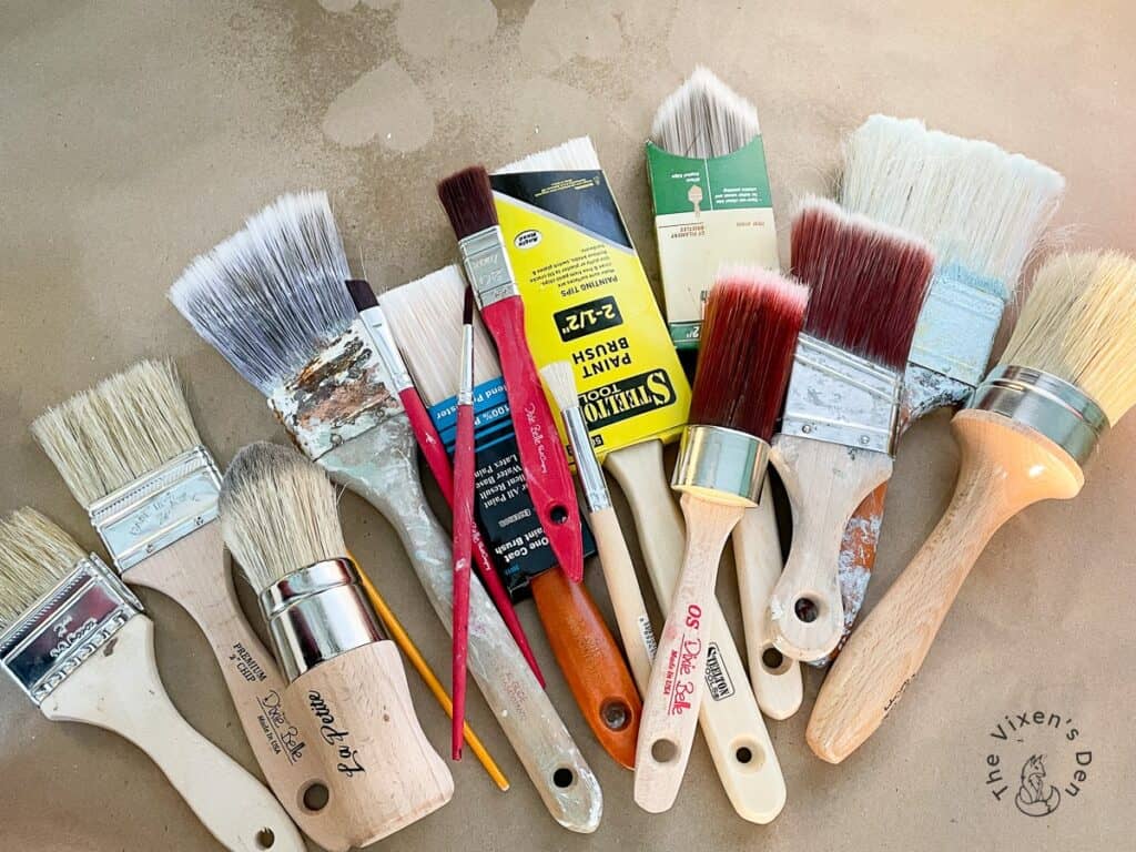 A group of paint brushes on a brown surface.