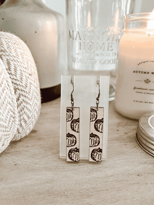 A pair of earrings on a table next to a candle.