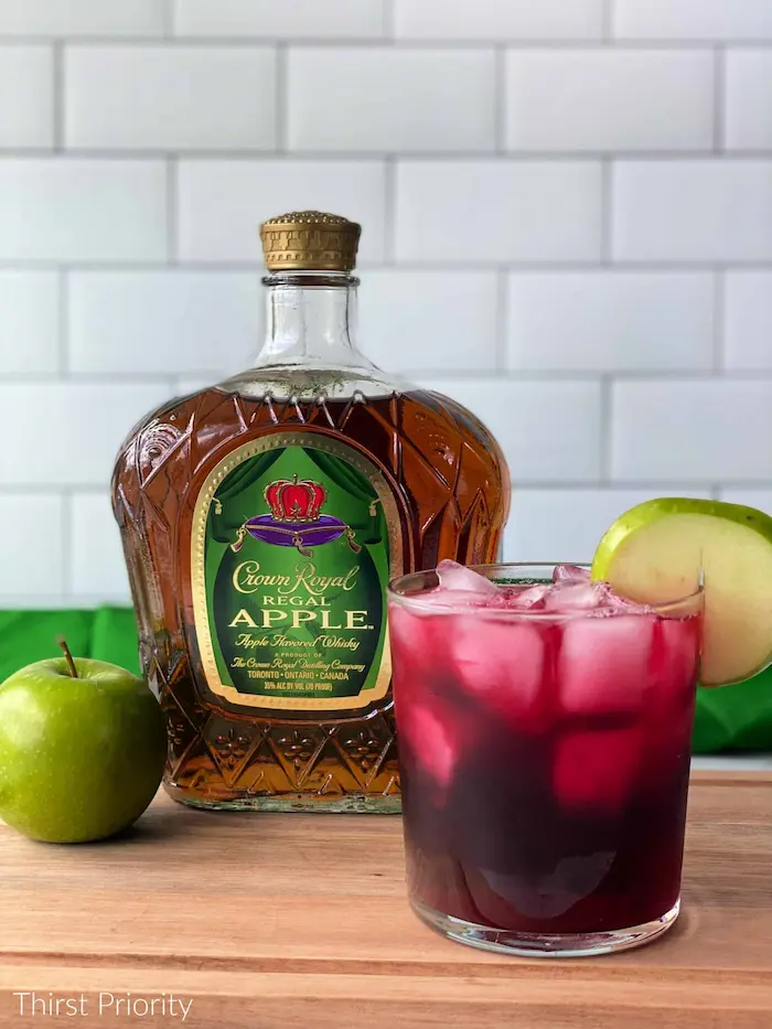 A bottle of rum and a bottle of apple juice on a cutting board.