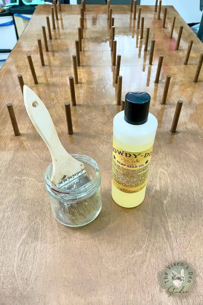 A wooden table with a bottle of hemp seed oil and a brush.
