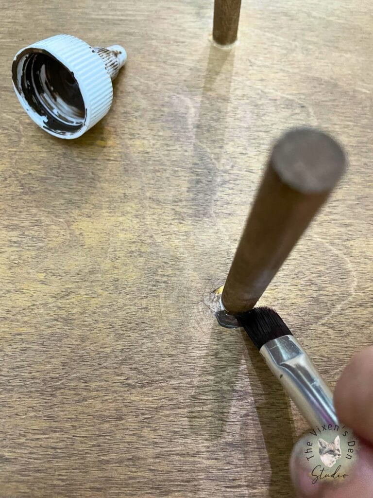 A person using a paint brush on a wooden table.