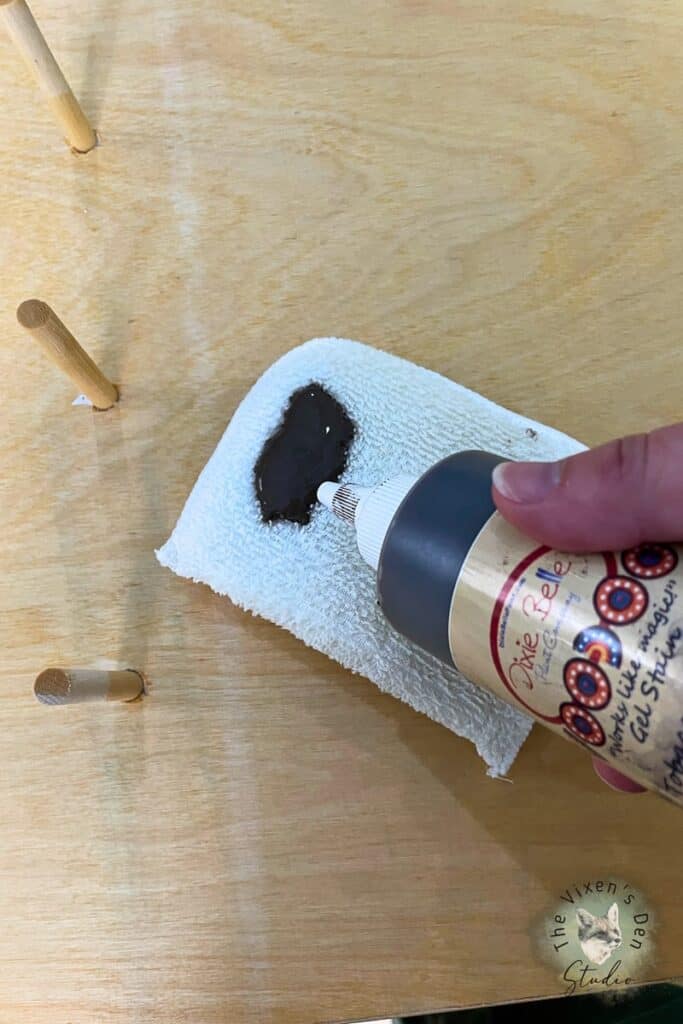A person is putting stain on an applicator on a wooden board.