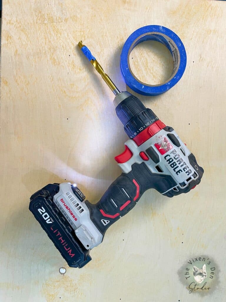 A cordless drill next to a roll of tape.