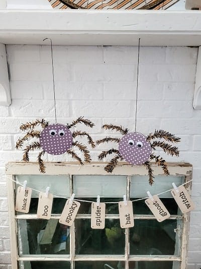 Two spiders hanging from a fireplace mantle.