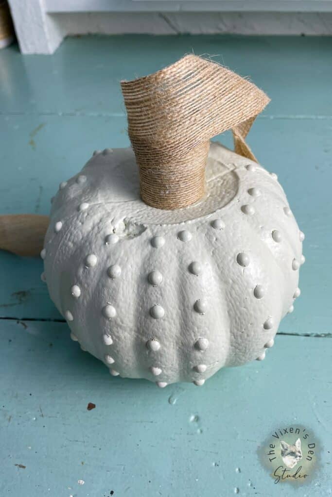 A white painted pumpkin on a wooden table.