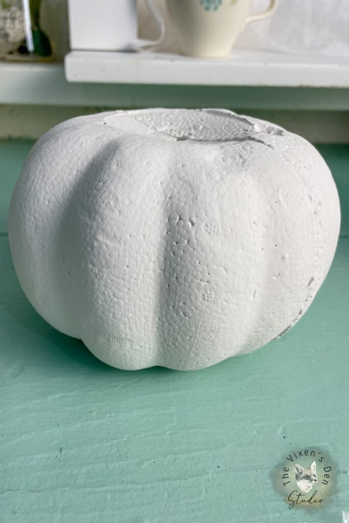 A white pumpkin sitting on a green table.