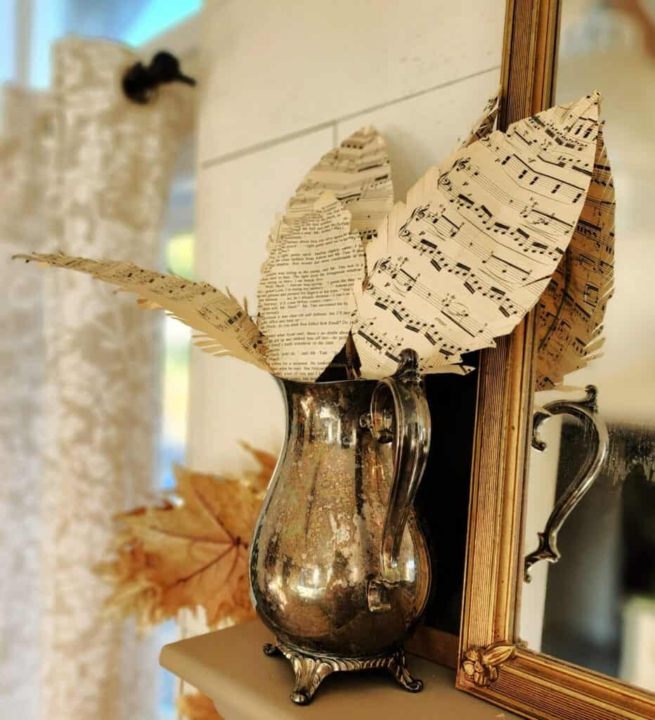 Paper leaves in a vase on top of a mantel.