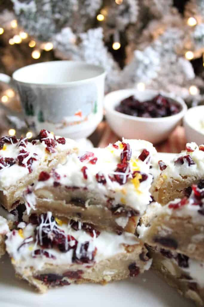Cranberry bars on a plate with a cup of coffee.