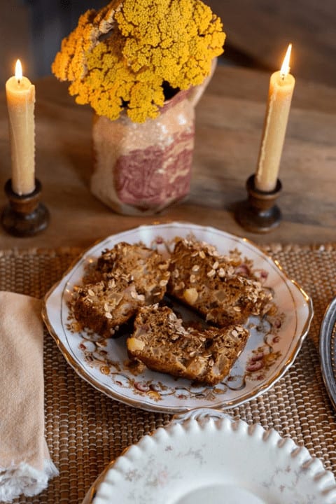 A table setting with candles and a plate of apple cake.