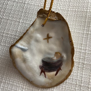 An oyster shell ornament with a cross on it.