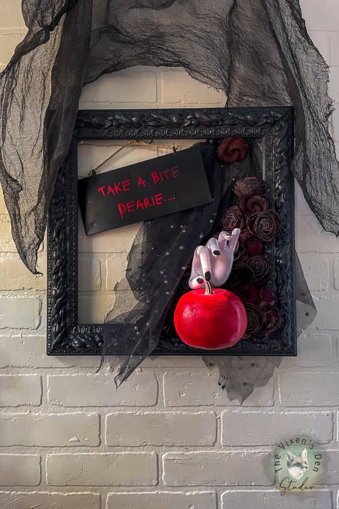 A black frame with a white hand holding a red apple.