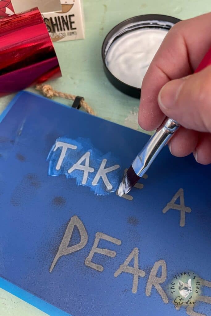 A person using a paint brush to paint a sign.