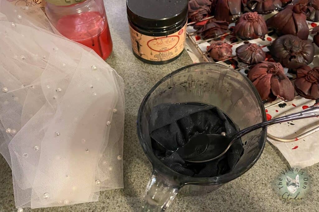 A bowl of black dye and a spoon on a counter.