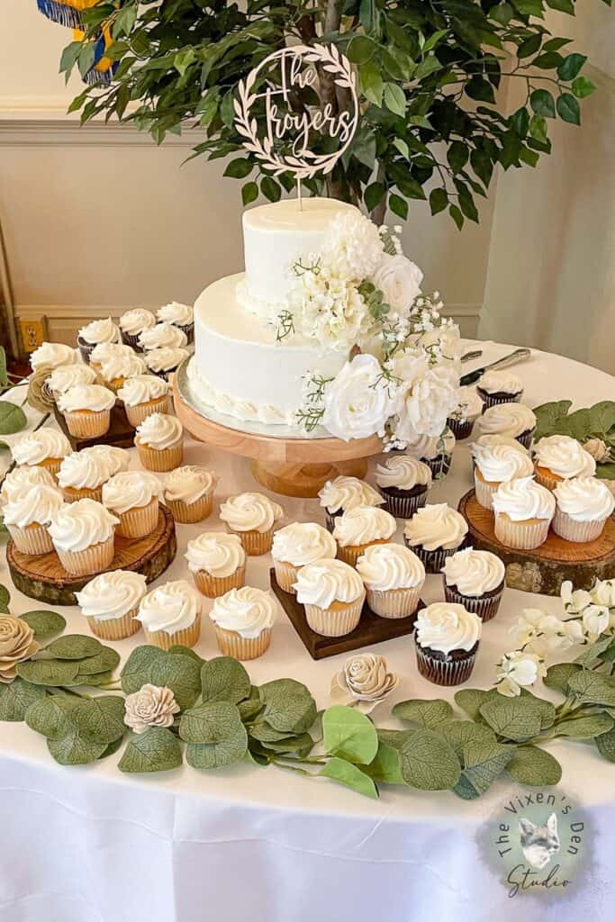 A wedding cake and cupcakes on a table.