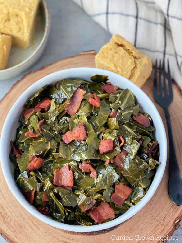 A bowl of collard greens with bacon and bread.