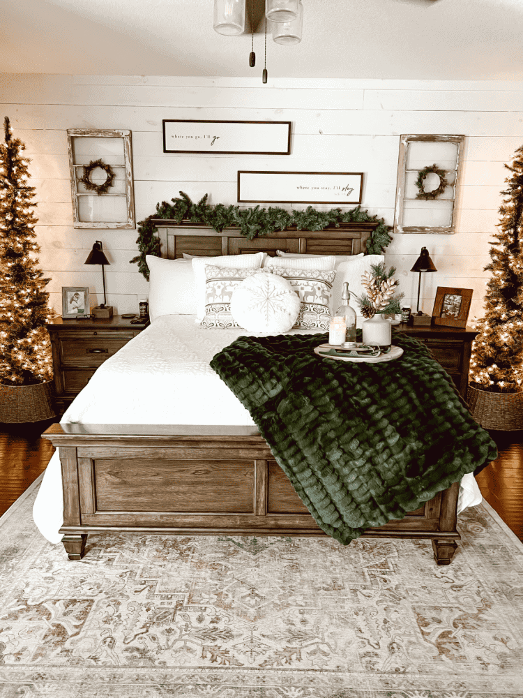 A bedroom decorated with christmas trees and a bed.