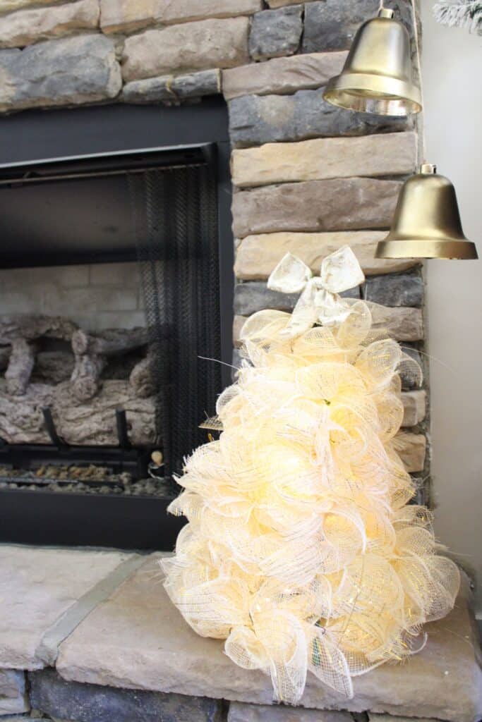 A white christmas tree in front of a stone fireplace.