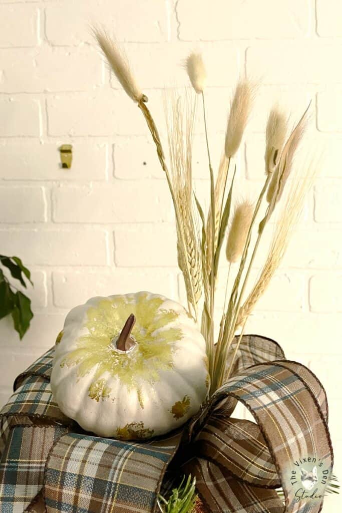 A pumpkin is sitting on top of a plaid tablecloth.