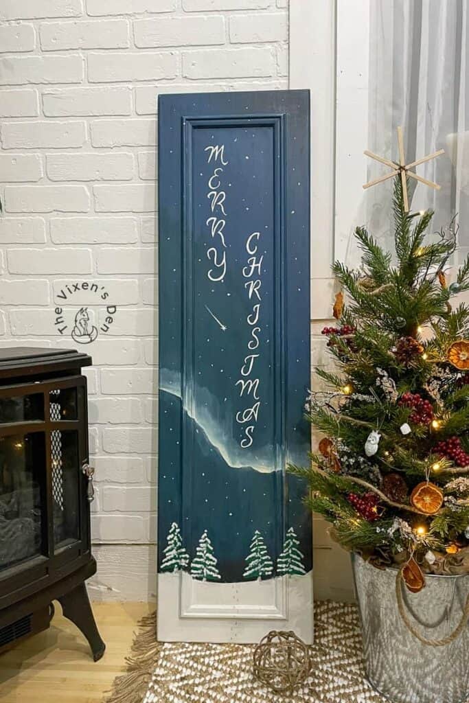 A wooden door with a painting of a christmas tree.