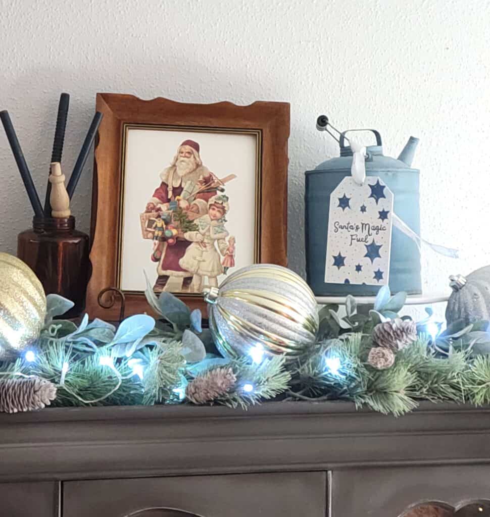 A mantle decorated with christmas ornaments and a santa claus sign.
