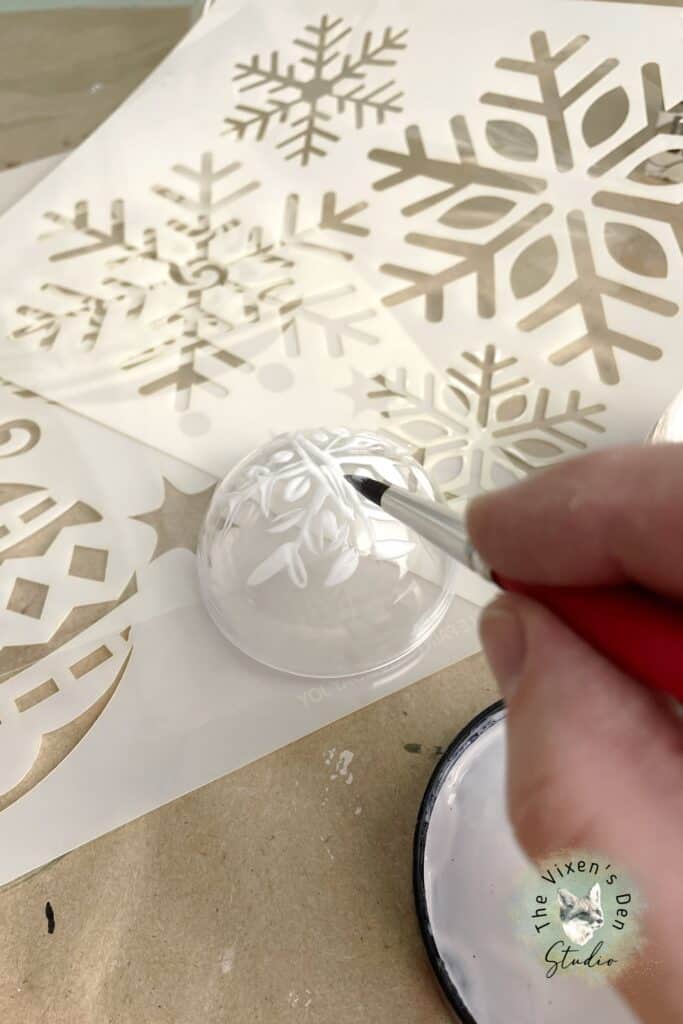 A person is using a paint brush to paint a snowflake on a piece of paper.