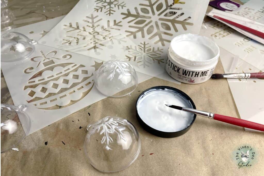 Snowflake ornaments with paint and brushes on a table.